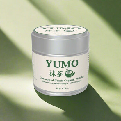 YUMO ceremonial grade organic matcha container on a green background